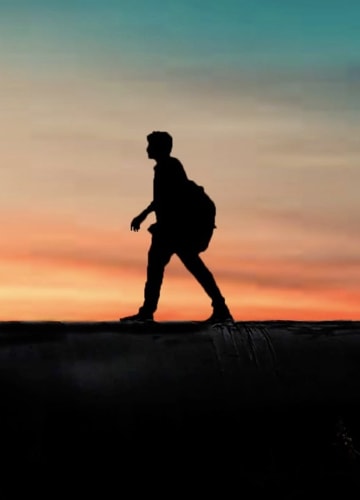 A portrait shot of a single male traveller walking
                     horizontally accross the cameras field of view, taken with a
                     rich orange and red sunset in the background