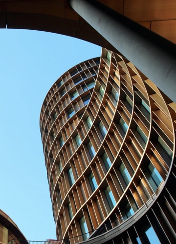 A low angle shot of a modern circular office-like building,
                        taken with a bright blue sky in the background