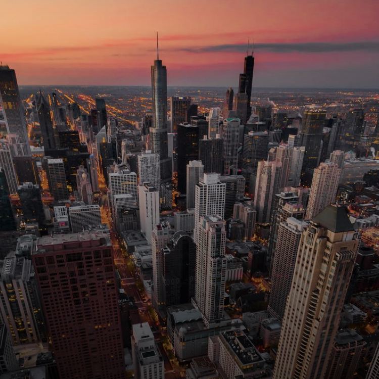 A wide angle arial shot of a city during sunset, looking down
                     upon the tall buildings and busy life below