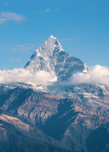 A wide angle shot of a pair of mountains, taken on a sunny day
                           with the bright blue sky in the background